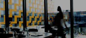 Background image of conference room in modern office with blurred shape of businesswoman crossing it